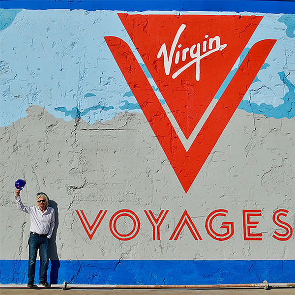Sir Richard Branson in Front of Virgin Voyages Logo